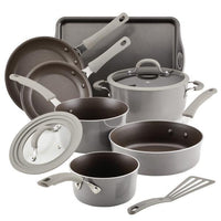 Cook + Create Nonstick Cookware Sets on display, showcasing aluminum pots and pans, tempered glass lids, a baking tray, and a spatula.