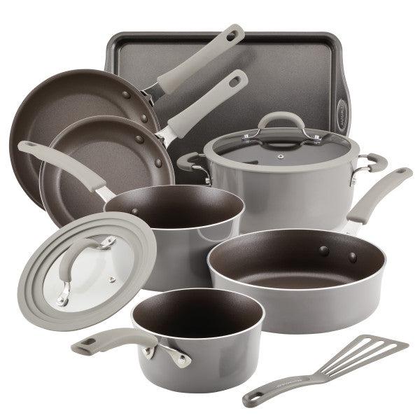 Cook + Create Nonstick Cookware Sets on display, showcasing aluminum pots and pans, tempered glass lids, a baking tray, and a spatula.