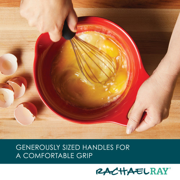 Hands whisking eggs in a set of red ceramic mixing bowls with eggshells nearby, highlighting the practicality and style of the 2-Piece Ceramic Mixing Bowl Set.