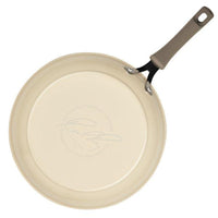 The Cook + Create Nonstick Frying Pan Set (2-Piece) includes a beige frying pan made from aluminum, boasting a signature on its bottom and complemented by a sleek gray handle.