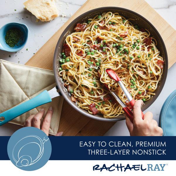 A person is stirring pasta in a Cook + Create Nonstick Frying Pan using red tongs, ensuring even cooking.