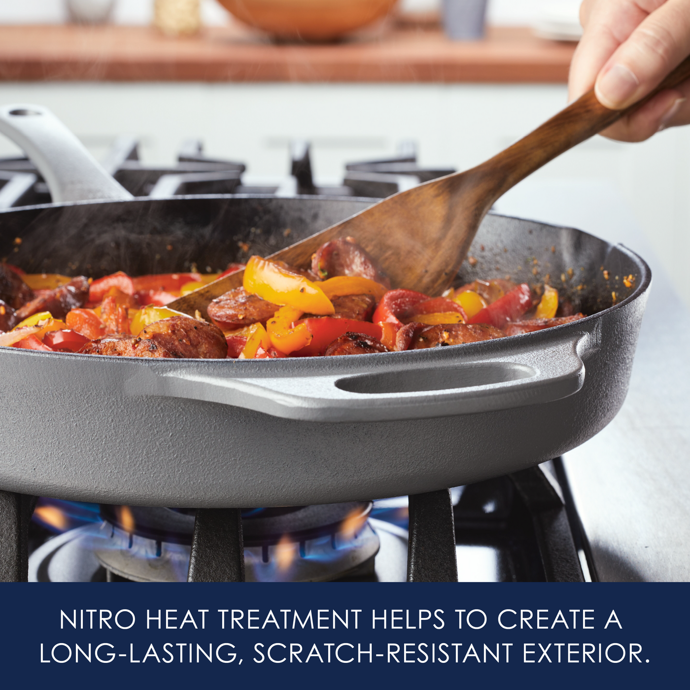A cast iron skillet on a stove, cooking vegetables and sausages.