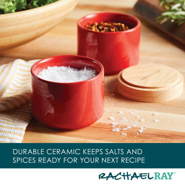 The Stacking Spice Box Set, crafted in red ceramic and filled with salt and spices, adorns a wooden kitchen counter.
