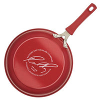 The Cook + Create Nonstick Frying Pan, a high-performance kitchen essential made from thicker gauge aluminum, features its signature and brand name on the bottom and comes in a vibrant red color.
