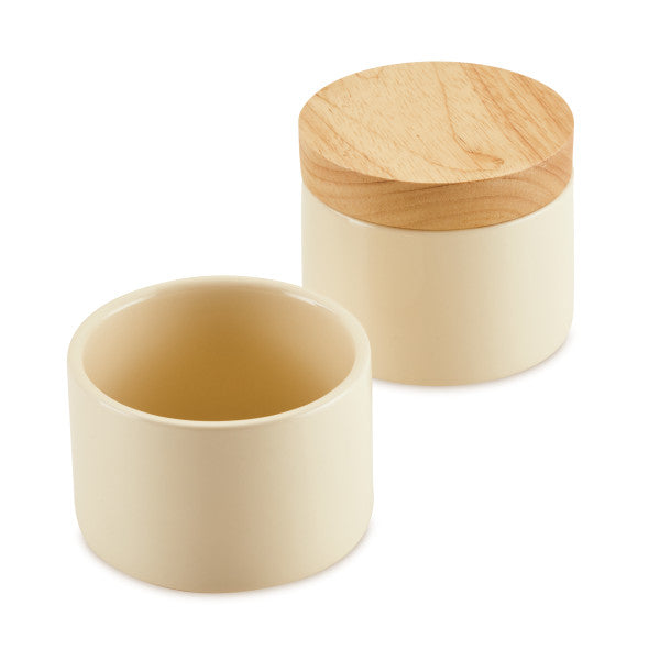 The Stacking Spice Box Set features two cream-colored ceramic containers with elegant wooden lids, beautifully combining functionality and style for storing spices.