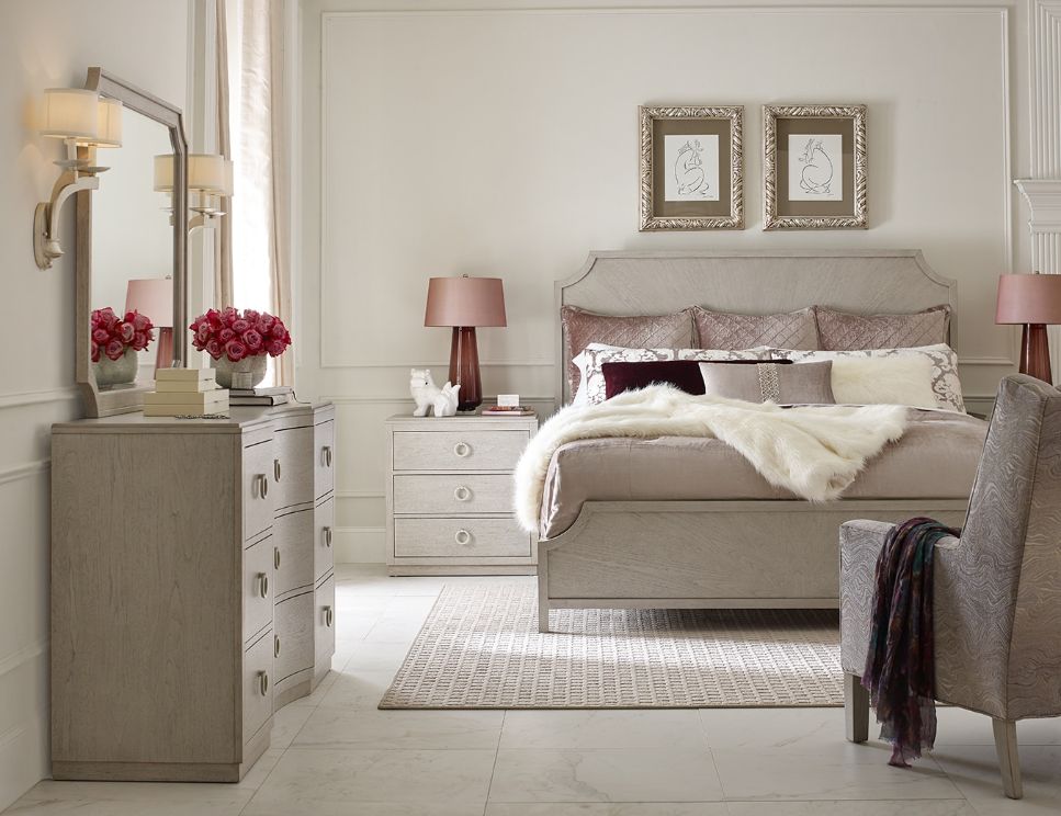 Elegant bedroom with a bed, dresser, chair, and wall art.
