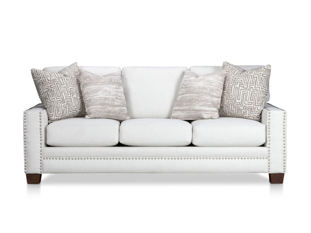 White sofa with patterned cushions and nailhead trim.