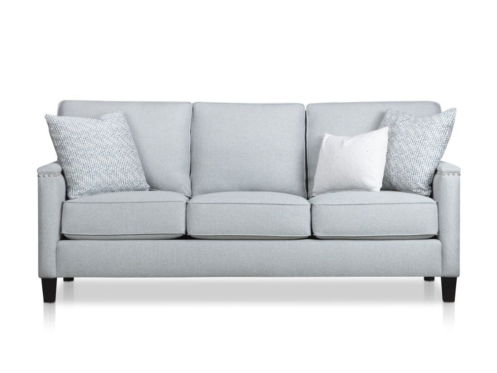 Gray sofa with three white and patterned pillows.