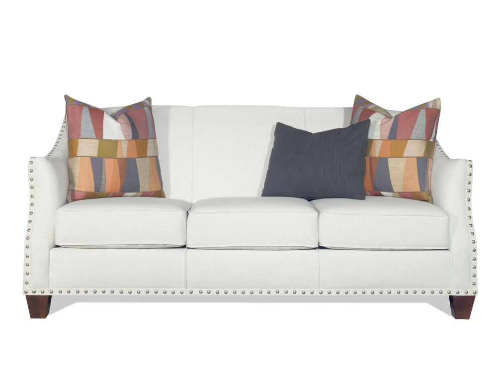 White sofa with decorative pillows featuring colorful patterns and nailhead trim.