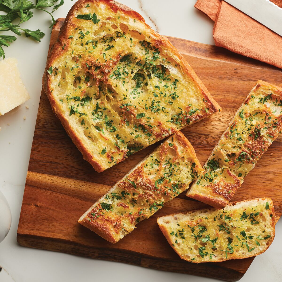 Slices of garlic bread with herbs on a wooden board.