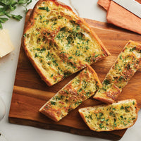Slices of garlic bread with herbs on a wooden board.