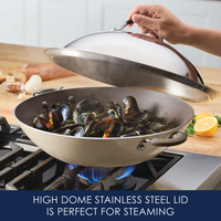 A person lifts the 14-Inch Stainless Steel Domed Lid from a pot of steaming mussels.