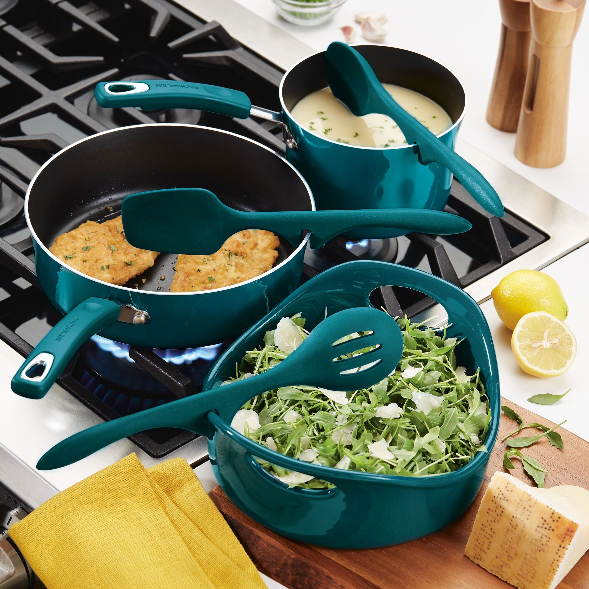 The cookware set features pans, soup, and salad on a stovetop, accompanied by the versatile 3-Piece Lazy Tool Set.