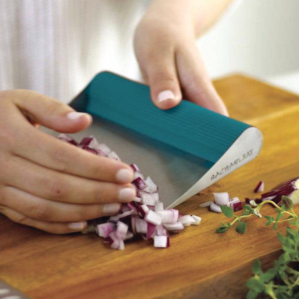 A person utilizes Rach's Food Mover to efficiently gather diced onions from the cutting board.