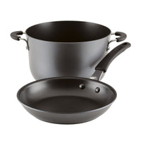 The 10-Piece Cook + Create Hard Anodized Nonstick Cookware Set is made from hard-anodized aluminum and includes a cooking pot and frying pan with black handles, all displayed against a pristine white background.