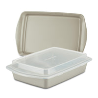 The 3-Piece Nonstick Covered Cake Pan & Baking Sheet Set, featuring a beige pan made from heavy gauge steel, includes a snug-fitting lid that nests inside a larger one, making it ideal for all your baking endeavors.