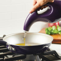 Transfer oil from the 24-Ounce EVOO Bottle into a frying pan on the stove using precision pouring, assisted by a stainless steel pour spout.