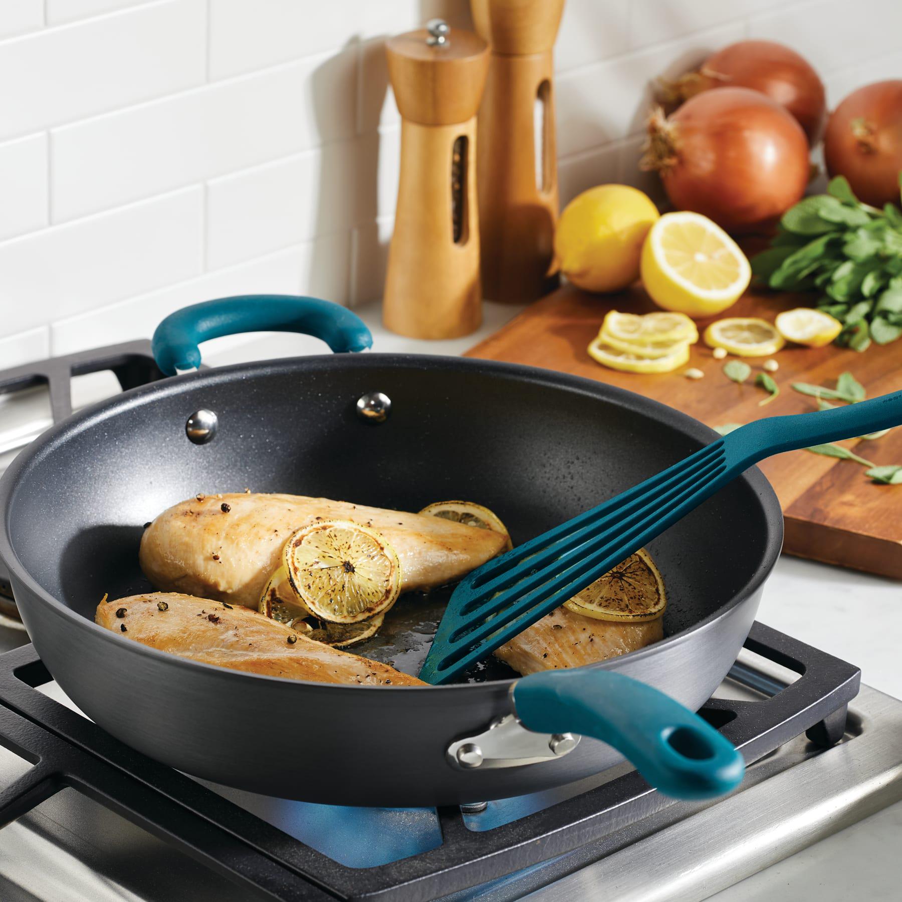 Chicken breasts and lemons cook in a 12.5" nonstick deep frying pan on the stove.
