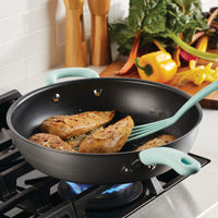 Chicken breasts and veggies cooking in a 12.5" nonstick deep frying pan on the stove.